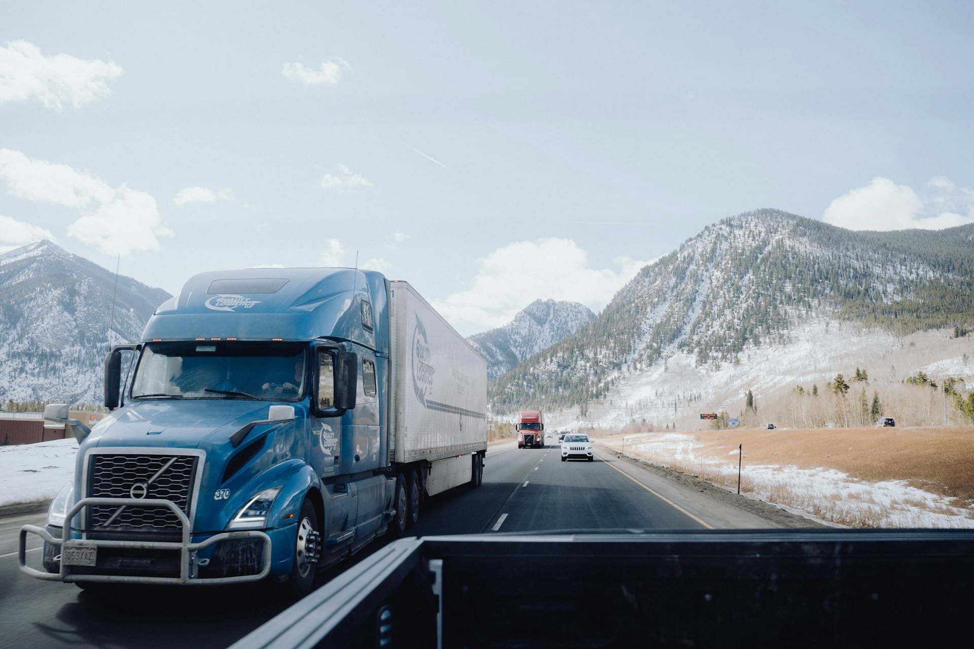 Blue semi-truck with a white trailer driving on a highway